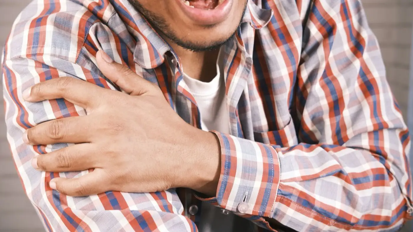 Hombre adulto se sujeta el hombro con la mano contraria